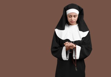 Kahverengi arka planda genç bir rahibenin portresi