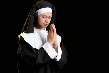 Siyah arka planda dua eden genç bir rahibe