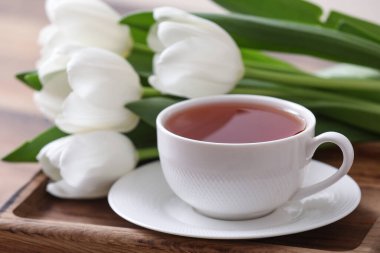 Bulanık arka planda sıcak çay ve lalelerle dolu bir tepsi