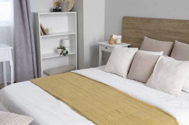 Yataklı, raflı, yastıklı ve komodinli bir yatak odası.