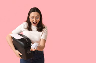 Pembe arka planda kağıt öğütücüsü olan mutlu sekreter