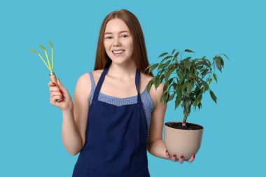 Mavi arka planda çiçek ve bahçe aletleri olan güzel genç bir kadın.