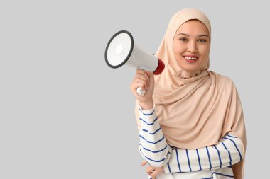Gri arka planda megafonu olan genç Asyalı Müslüman kadın. Ulusal Duyulma Günü
