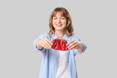 Gri arka planda kırmızı çanta tutan güzel genç kadın, yakın plan.