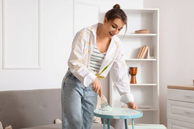 Evde fırça tablosu olan genç bir kadın.