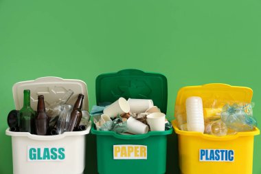 Yeşil duvarın yanında farklı geri dönüşüm kutuları var. Geri dönüşüm kavramı