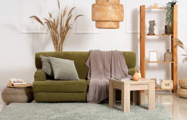 Yeşil kanepesi, masası ve otları olan rahat bir oturma odası.