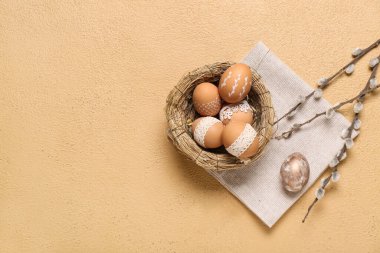 Paskalya yumurtaları ve kahverengi arka planda söğüt dalları olan yuva