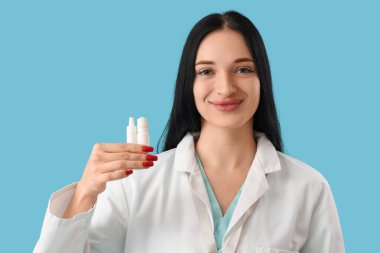 Mavi arka planda göz damlası olan kadın göz doktoru, yakın plan.