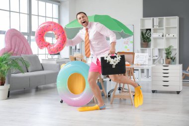 Ofiste bavulu ve şişirilebilir yüzükleri olan mutlu bir ofis çalışanı. Yaz tatili kavramı