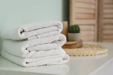 Yatak odasındaki masada temiz yumuşak havlu yığını, yakın plan.