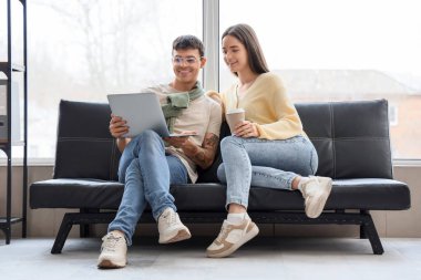 Ofisteki kanepede dizüstü bilgisayarla çalışan iki programcı.