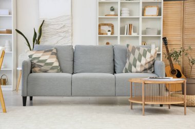 Oturma odasının içi rahat gri kanepe ve ahşap sehpa ile dolu.