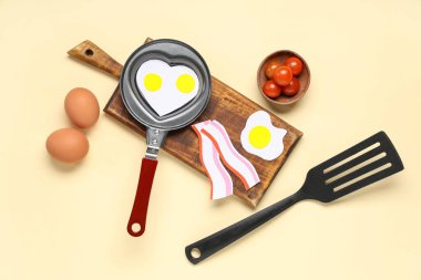 Kağıt yumurta, pastırma ve bej arka planda malzemeyle kalp şeklinde kızartma tavası.