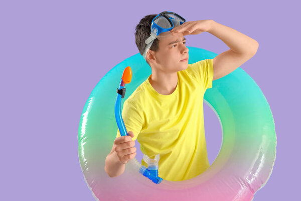 Симпатичный маленький мальчик с надувным кольцом и маской для подводного плавания на фиолетовом фоне