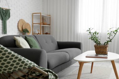 Kahve masası, koltuk ve kanepe üzerinde bambu sapları olan modern oturma odasının içi aydınlık.