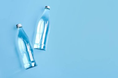 Mavi zemin üzerinde cam temiz su şişeleri