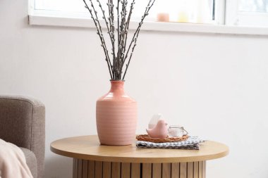 Oturma odasında söğüt dalları ve dekoru olan pembe vazo, yakın plan.