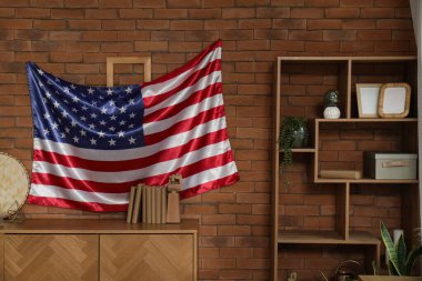 Çekmeceli şık bir oda ve kahverengi tuğla duvarda Amerikan bayrağı.