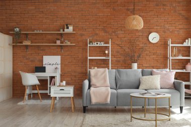 Oturma odasının içinde kanepe, işyeri ve vazoda söğüt dalları var.