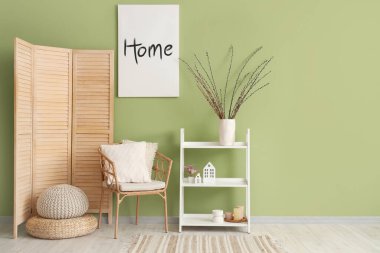 Hasır koltuğu, raf ünitesi ve vazoda söğüt dalları olan şık bir oturma odası.