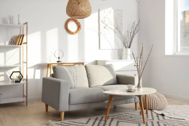 Kanepe, masa ve vazolarda söğüt dallarıyla aydınlık oturma odasının içinde.