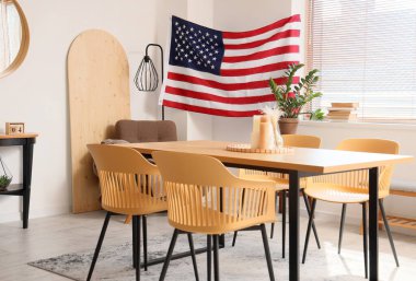 Sandalyeleri, masası ve duvarında ABD bayrağı olan hafif yemek odası.
