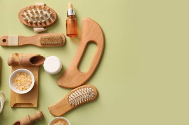 Ahşap guasha vücut masajı aracı ve yeşil arka planda banyo malzemeleri ile kompozisyon
