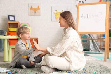 Kadın psikolog ve küçük çocuk ofiste birbirlerine beşlik çakıyorlar. Dünya Otizm Farkındalık Günü