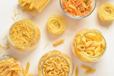 Hafif arka planda cam kaselerde farklı pişirilmemiş makarna kompozisyonu