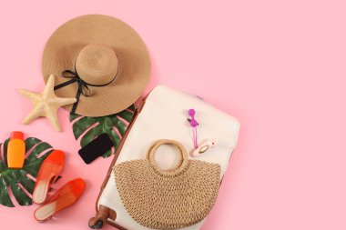 Çantalı kompozisyon, plaj aksesuarları, cep telefonu ve pembe arka planda seks oyuncakları.