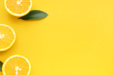 Renkli arkaplanda olgun portakal ve yeşil yapraklı kompozisyon