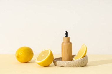 Limonlu kompozisyon, taş tepsi ve hafif arka planda bir şişe kozmetik ürünü.