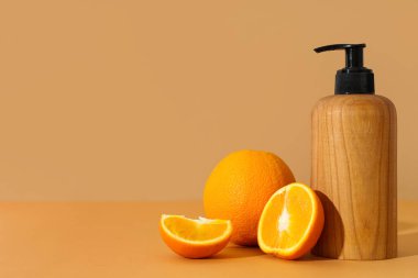 Kahverengi arka planda bir şişe kozmetik ürünü ve portakallı kompozisyon
