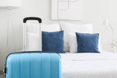 Hafif otel odasında, yatağın yanında bavul, yakın plan.