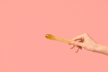 Pembe arka planda şekerli spatula tutan kadın.