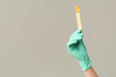 Gri arka planda şekerli spatula tutan kadın.