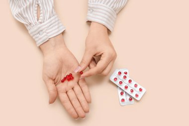 Bej arka planda kırmızı haplı kadın elleri