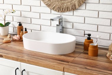 Lavabolu çekmeceler ve banyodaki beyaz tuğla duvarın yanında kozmetik ürünler.