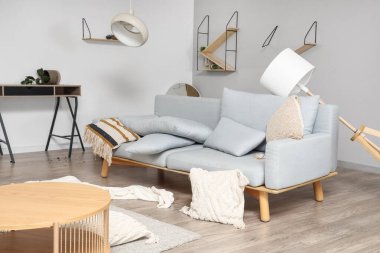 Dağınık oturma odasında ters dönmüş lambalı kanepe.