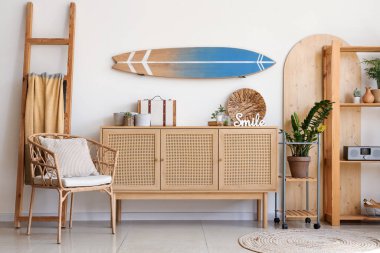 Oturma odasında dekorlu çekmecelerin duvarında ve sandığında sörf tahtası asılı.