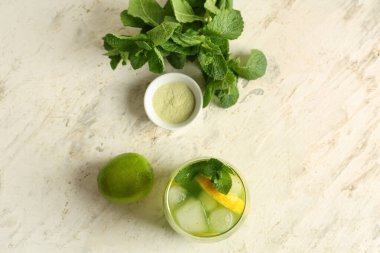 Beyaz arka planda naneli ve limonlu bir bardak lezzetli limonata.