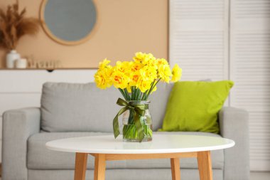 Oturma odasındaki sehpanın üzerinde nergis çiçekleri olan vazo.