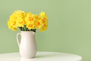 Nergis çiçekleri sehpanın üzerinde yeşil arka planda.