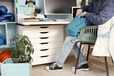 Evde sırt çantasında not defteri olan genç bir çocuk.