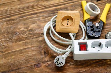 Tahta arka planda elektrik aletleri, soket ve uzatma kablosu