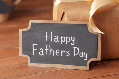 Yazılı kağıt Mutlu Babalar Günü ve hediye paketi ahşap arka planda.