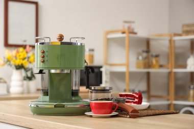 Modern kahve makinesi, bir fincan espresso ve mutfaktaki ahşap masada kek.