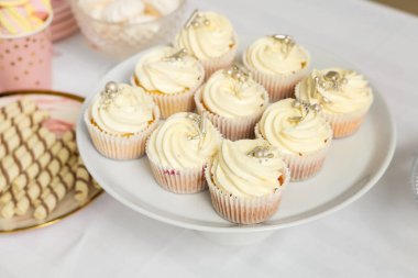 Doğum günü partisi için lezzetli beyaz kekleri olan tatlı standı masada, yakın plan.