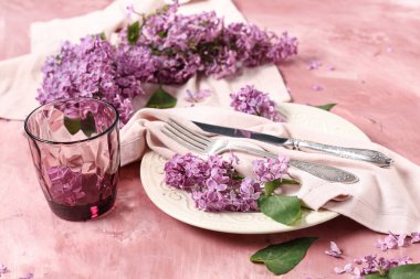 Pembe grunge arka planında leylak çiçekleri olan güzel bir masa, yakın plan.